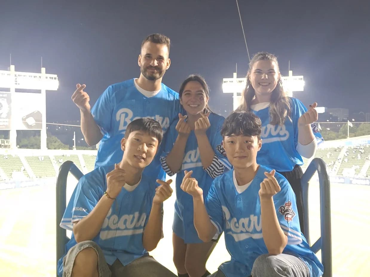 야간 잠실야구장에서 두산 유니폼을 입고 손가락 하트를 만든 게스트들